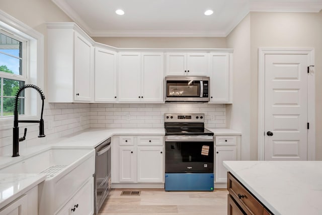 2121 Halls Mill Rd, Unionville, TN 37180 - kitchen featuring stainless steel appliances, a sink, white cabinets, tasteful backsplash, and crown molding