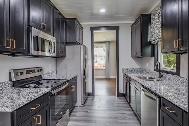 601 Lawrence St, Old Hickory, TN 37138 - kitchen featuring appliances with stainless steel finishes, a sink, light wood-type flooring, light stone counters, and dark cabinets
