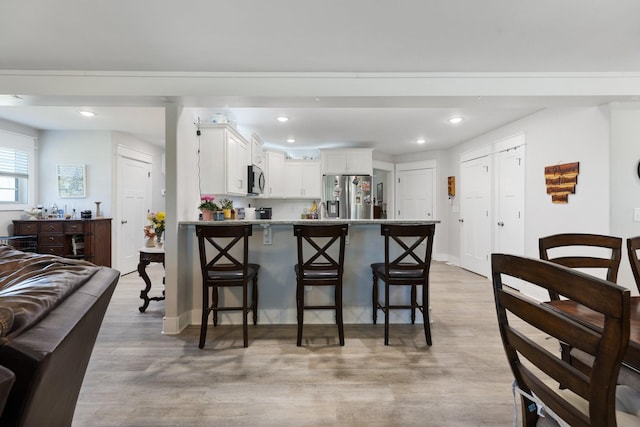 3021 Cambridge Ct, Lewisburg, TN 37091 - kitchen with appliances with stainless steel finishes, a peninsula, a kitchen bar, light wood-style floors, and white cabinetry