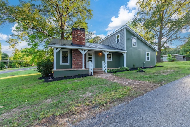 2897 Old Medina Rd, Jackson, TN 38305 - view of front of house featuring a chimney, covered porch, a front yard, and metal roof