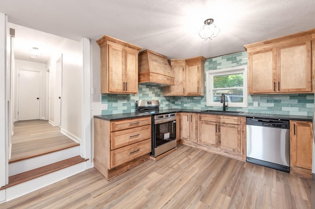 2897 Old Medina Rd, Jackson, TN 38305 - kitchen with appliances with stainless steel finishes, a sink, premium range hood, dark countertops, and light wood-type flooring