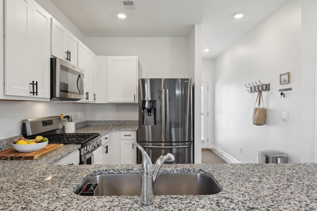 1507 Ashgrove Pl, Lebanon, TN 37087 - kitchen with stainless steel appliances, a sink, light stone countertops, white cabinetry, and recessed lighting
