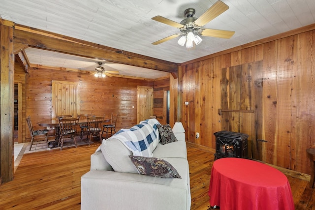 102 Nall Ave, Centerville, TN 37033 - living room with a wood stove, wood walls, a ceiling fan, wood finished floors, and beamed ceiling