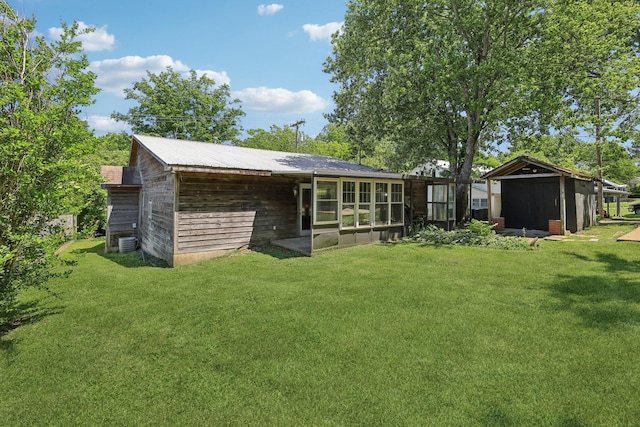 102 Nall Ave, Centerville, TN 37033 - back of house with a lawn, a sunroom, central AC, and an outdoor structure