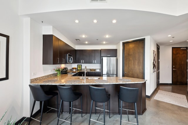 1510 Demonbreun St Unit 711, Nashville, TN 37203 - kitchen featuring stainless steel appliances, a peninsula, light stone counters, dark brown cabinetry, and recessed lighting
