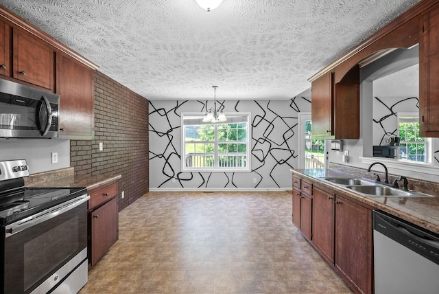 1382 Whitt Ln, Clarksville, TN 37042 - kitchen featuring appliances with stainless steel finishes, a sink, brick wall, pendant lighting, and a textured ceiling