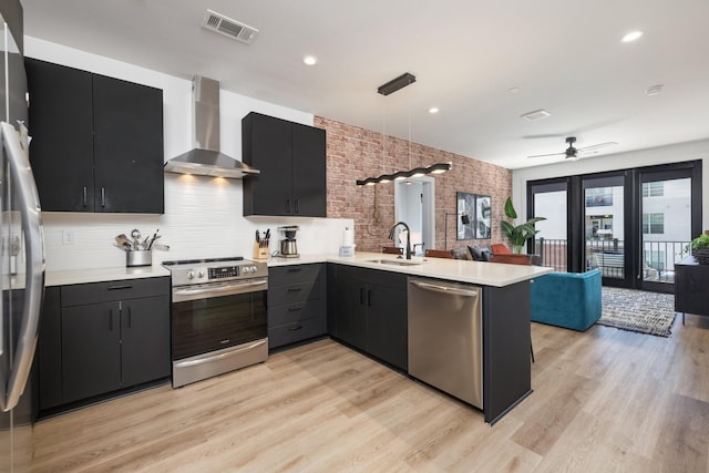 303 31st Ave N Unit 305, Nashville, TN 37203 - kitchen featuring appliances with stainless steel finishes, wall chimney exhaust hood, a sink, dark cabinetry, and a peninsula