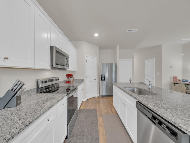 108 Birdie Ct, Dickson, TN 37055 - kitchen featuring stainless steel appliances, a sink, light wood finished floors, white cabinets, and light stone countertops