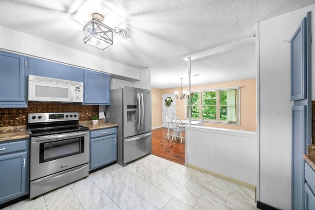160 Terrapin Run Rd, Dover, TN 37058 - kitchen featuring appliances with stainless steel finishes, blue cabinets, a chandelier, a textured ceiling, and decorative backsplash