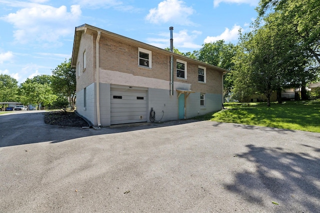 221 Cedar Creek Dr, Mount Juliet, TN 37122 - back of property featuring an attached garage, asphalt driveway, brick siding, and a lawn