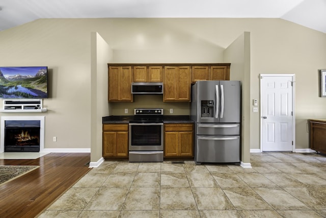 2815 Windy Way, Thompsons Station, TN 37179 - kitchen featuring appliances with stainless steel finishes, brown cabinets, dark countertops, baseboards, and high vaulted ceiling