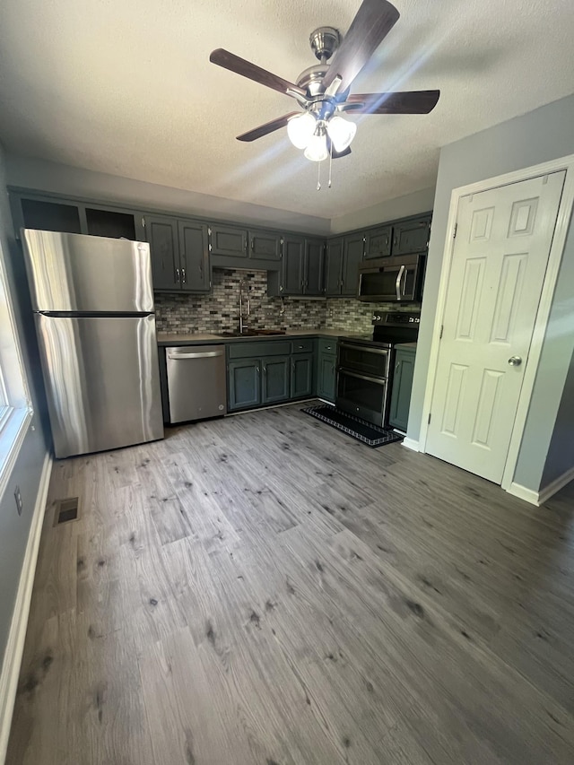 924 Granny White Rd, Clarksville, TN 37040 - kitchen featuring stainless steel appliances, a sink, a ceiling fan, wood finished floors, and decorative backsplash