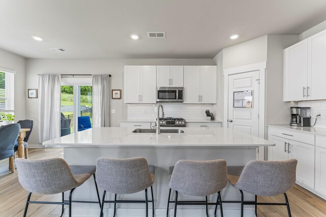 360 Gulfstream Dr, Gallatin, TN 37066 - kitchen with stainless steel microwave, a sink, a kitchen breakfast bar, white cabinets, and recessed lighting