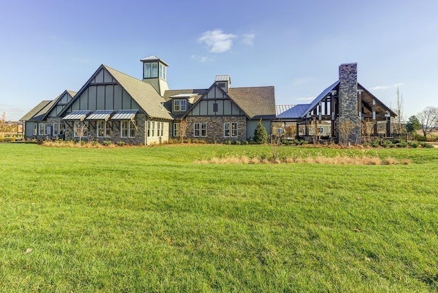 155 Salton Ln, Spring Hill, TN 37174 - back of house featuring stone siding, a yard, a standing seam roof, a chimney, and metal roof