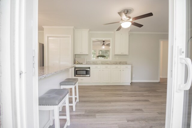 204 Tyne Blvd, Old Hickory, TN 37138 - kitchen with stainless steel microwave, ceiling fan, crown molding, light wood-style flooring, and light stone counters