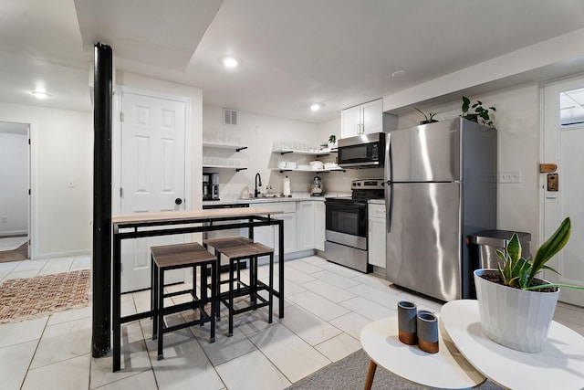 1211 Stratford Ave, Nashville, TN 37216 - kitchen featuring appliances with stainless steel finishes, open shelves, light countertops, white cabinetry, and recessed lighting