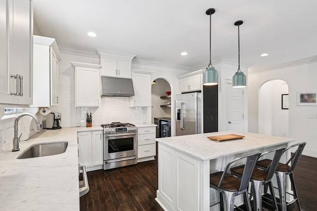 2809 Vaulx Ln, Nashville, TN 37204 - kitchen featuring stainless steel appliances, under cabinet range hood, arched walkways, crown molding, and dark wood-style flooring