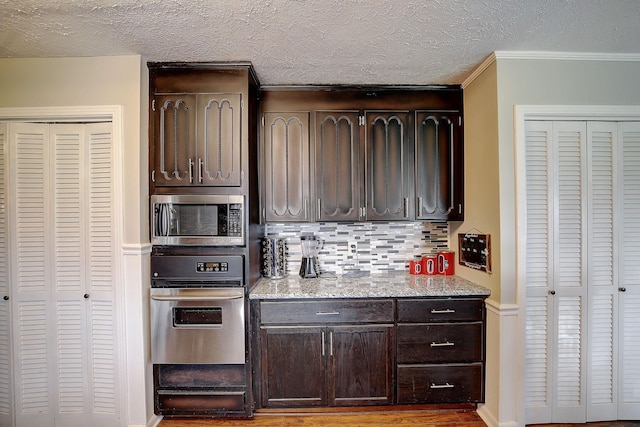 1611 Saltlick Pl, Murfreesboro, TN 37129 - kitchen featuring stainless steel appliances, tasteful backsplash, dark brown cabinetry, a textured ceiling, and ornamental molding