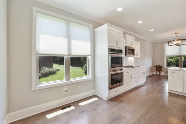 212 Lotus Ct, Hendersonville, TN 37075 - kitchen featuring appliances with stainless steel finishes, crown molding, wood finished floors, plenty of natural light, and white cabinets
