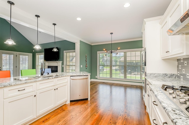 4423 Garcia Blvd, Murfreesboro, TN 37128 - kitchen featuring appliances with stainless steel finishes, wall chimney exhaust hood, a fireplace, a chandelier, and white cabinets
