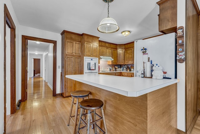 401 Ellington Dr, Franklin, TN 37064 - kitchen with oven, under cabinet range hood, light countertops, light wood-style floors, and brown cabinets