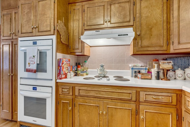 401 Ellington Dr, Franklin, TN 37064 - kitchen with under cabinet range hood, white appliances, decorative backsplash, and brown cabinetry