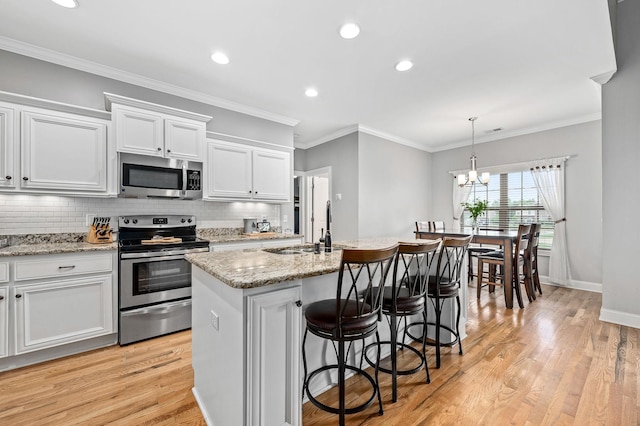 2520 Pebblecreek Ln, Murfreesboro, TN 37130 - kitchen with appliances with stainless steel finishes, light wood-style flooring, white cabinets, a kitchen island with sink, and recessed lighting