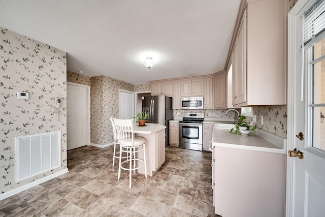 1101 Wedgewood Dr, Gallatin, TN 37066 - kitchen with appliances with stainless steel finishes, wallpapered walls, a sink, light countertops, and a kitchen bar
