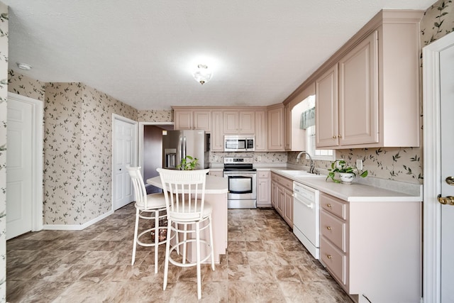 1101 Wedgewood Dr, Gallatin, TN 37066 - kitchen with stainless steel appliances, a sink, wallpapered walls, light countertops, and a breakfast bar area
