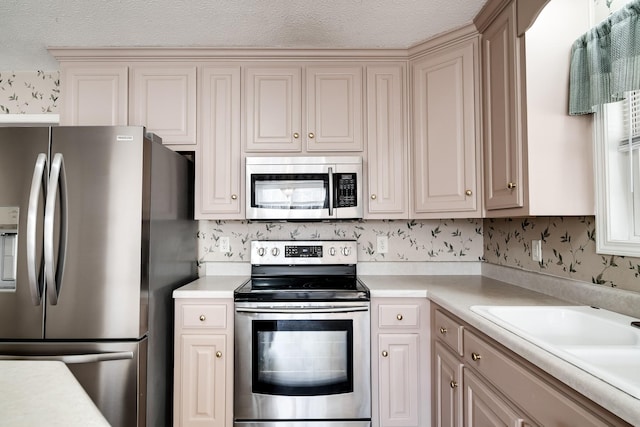 1101 Wedgewood Dr, Gallatin, TN 37066 - kitchen with appliances with stainless steel finishes, light countertops, wallpapered walls, a sink, and a textured ceiling
