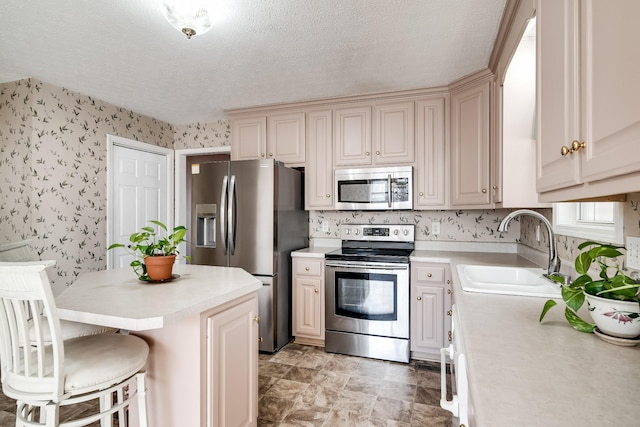 1101 Wedgewood Dr, Gallatin, TN 37066 - kitchen featuring stainless steel appliances, a sink, light countertops, wallpapered walls, and a kitchen breakfast bar