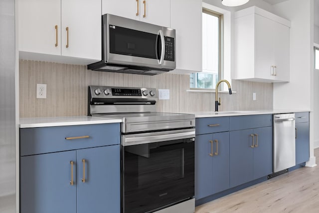 2522 E 18th St, Chattanooga, TN 37404 - kitchen featuring stainless steel appliances, blue cabinets, light countertops, light wood-style flooring, and a sink