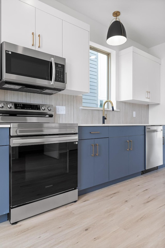 2522 E 18th St, Chattanooga, TN 37404 - kitchen featuring stainless steel appliances, blue cabinets, light countertops, and light wood finished floors