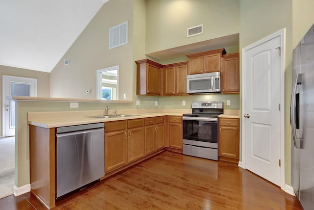 6001 Ten Bears Way, Spring Hill, TN 37174 - kitchen with appliances with stainless steel finishes, a sink, high vaulted ceiling, a peninsula, and wood finished floors