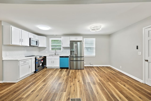 120 Johns St, La Vergne, TN 37086 - kitchen featuring stainless steel appliances, a sink, light wood-type flooring, white cabinets, and backsplash