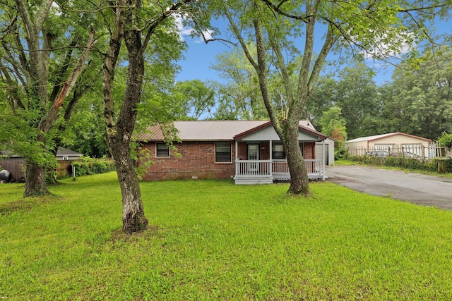 120 Johns St, La Vergne, TN 37086 - view of front of property featuring a porch, a front yard, brick siding, and metal roof