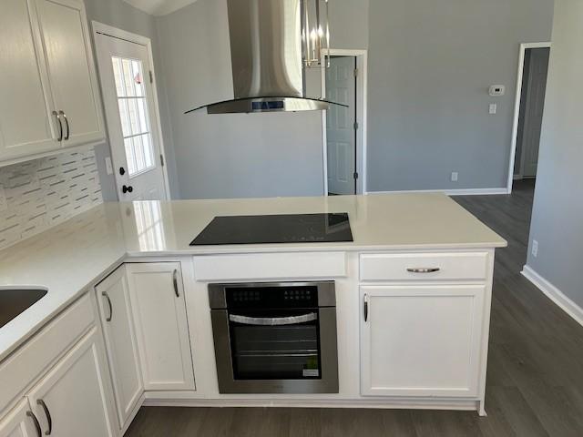 1047 Tylertown Rd, Clarksville, TN 37040 - kitchen featuring oven, wall chimney exhaust hood, black electric cooktop, white cabinets, and dark wood-type flooring