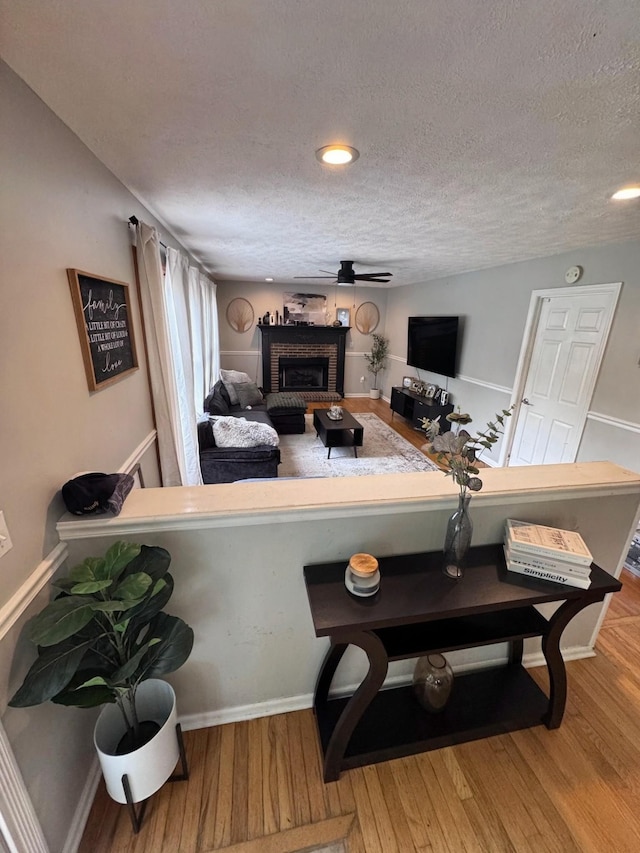 1111 Craig Moore Rd, Lewisburg, TN 37091 - living room with a textured ceiling, wood finished floors, a brick fireplace, baseboards, and ceiling fan