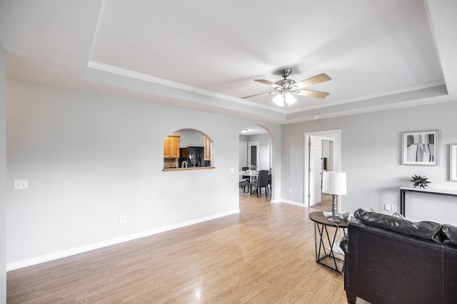 103 Alice Smith Dr, Portland, TN 37148 - living room featuring a tray ceiling, arched walkways, a ceiling fan, light wood finished floors, and baseboards
