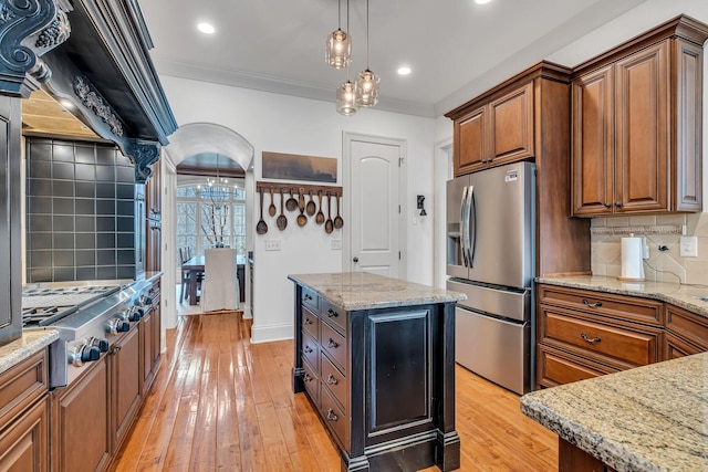 1120 Natchez Valley Ln, Franklin, TN 37064 - kitchen featuring stainless steel appliances, backsplash, brown cabinets, light stone countertops, and crown molding