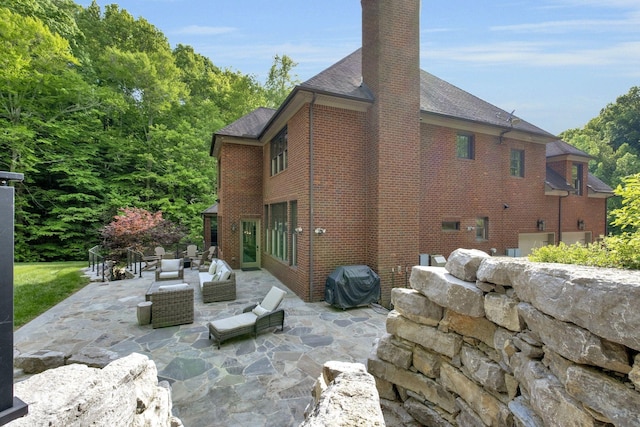 1120 Natchez Valley Ln, Franklin, TN 37064 - rear view of house featuring a chimney, a patio area, brick siding, a shingled roof, and an outdoor hangout area