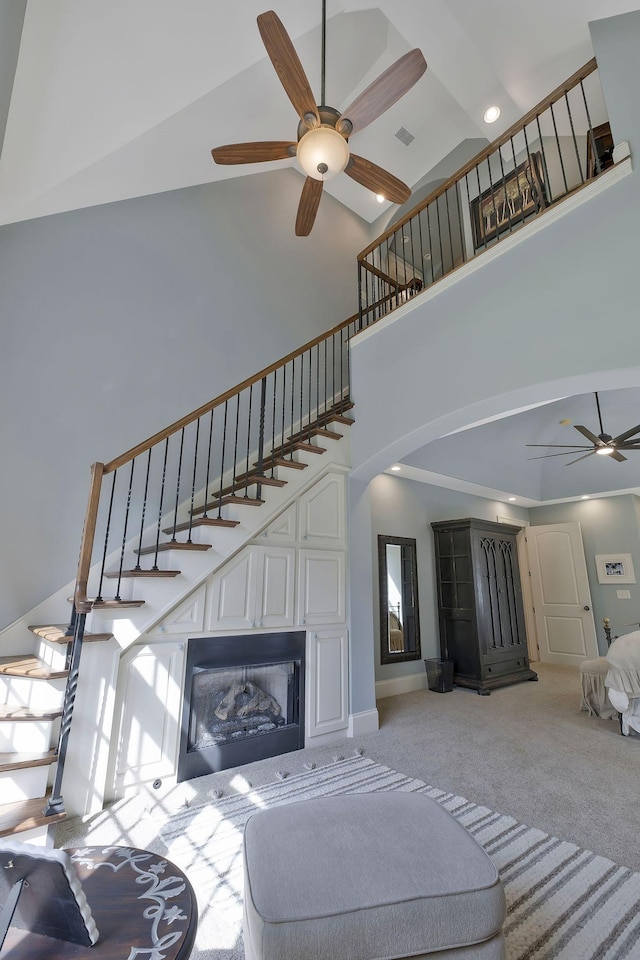 1120 Natchez Valley Ln, Franklin, TN 37064 - living room featuring ceiling fan, a towering ceiling, arched walkways, light carpet, and stairway