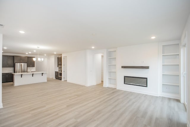 118 W Cassa Way, Mount Juliet, TN 37122 - unfurnished living room with built in shelves, recessed lighting, light wood-style floors, a glass covered fireplace, and baseboards