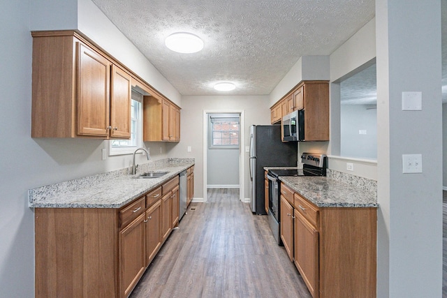 104 Evanmeade Dr, Smyrna, TN 37167 - kitchen featuring appliances with stainless steel finishes, a sink, wood finished floors, baseboards, and a textured ceiling