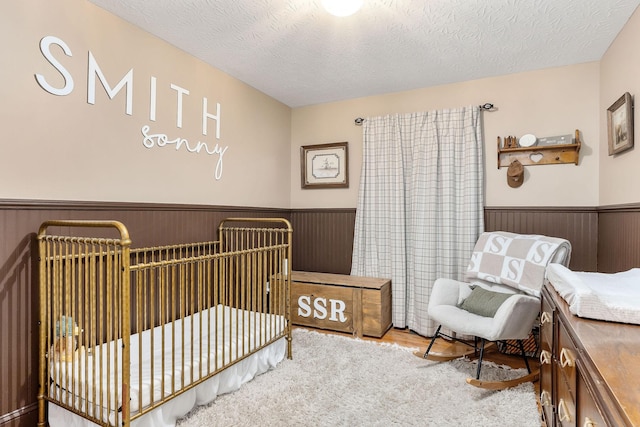 24 Hillcrest Dr, Sparta, TN 38583 - bedroom featuring wainscoting, a textured ceiling, wood finished floors, and a nursery area