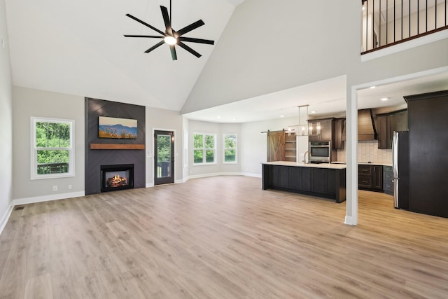 1373 Southside Rd, Southside, TN 37171 - unfurnished living room featuring high vaulted ceiling, ceiling fan, a large fireplace, light wood-style floors, and baseboards