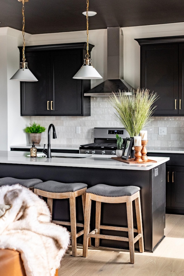 326A E Trinity Ln, Nashville, TN 37207 - kitchen with wall chimney exhaust hood, gas range, dark cabinets, and a kitchen breakfast bar