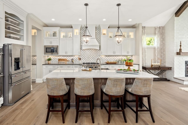 7243 Murrel Dr, Franklin, TN 37064 - kitchen featuring stainless steel appliances, premium range hood, backsplash, and a kitchen bar