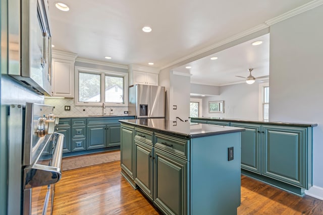 1135 Riverwood Dr, Nashville, TN 37216 - kitchen featuring appliances with stainless steel finishes, dark countertops, a kitchen island, healthy amount of natural light, and crown molding