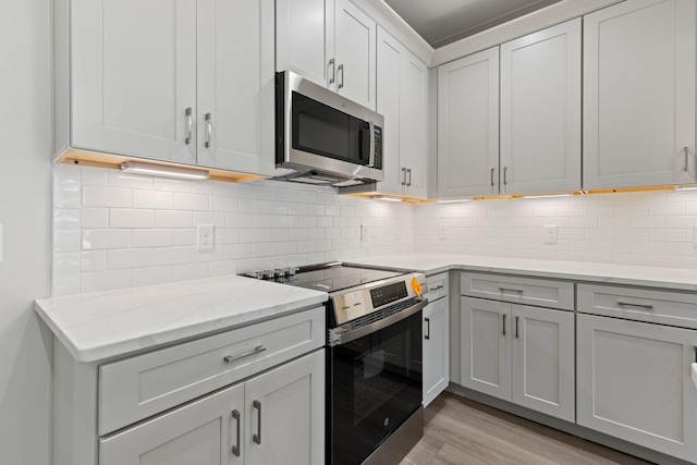 5509 Urbandale Ave, Nashville, TN 37209 - kitchen with stainless steel appliances, tasteful backsplash, light wood-type flooring, and light stone countertops